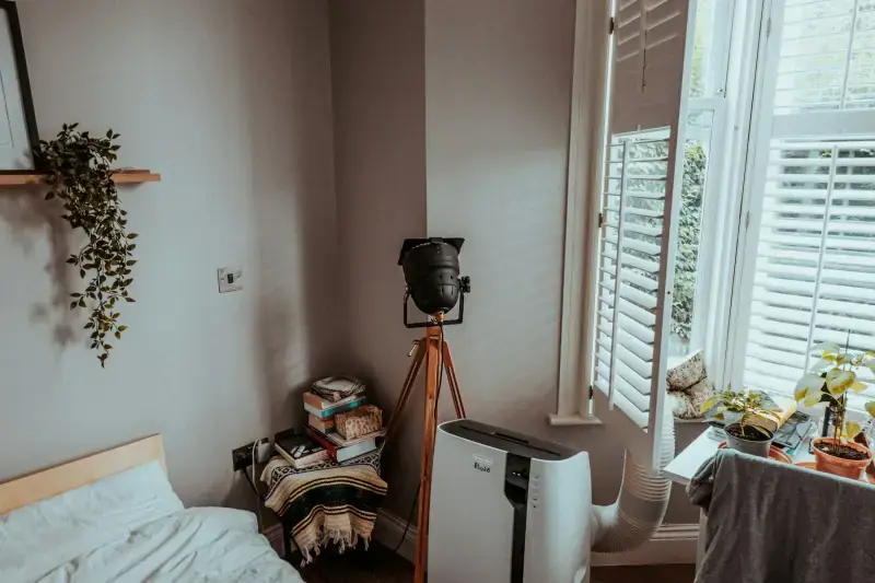 Portable air unit with its hose venting out a bedroom window