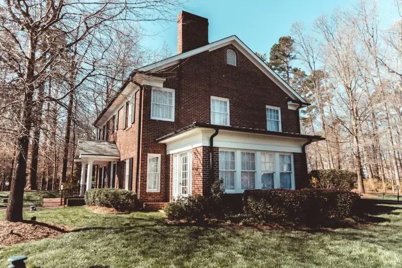 Brick two-story house among bare winter trees