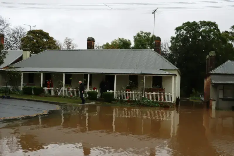 Floodwater across the street in front of a single-story porch house